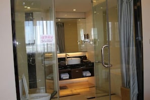 A modern bathroom with a glass shower enclosure, a sink, and a vanity with a mirror.