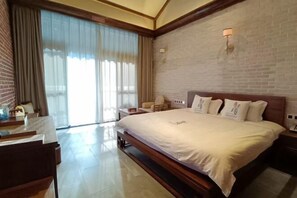 Une chambre d’hôtel avec un grand lit, un bureau, une chaise et une vue par la fenêtre, qui est dotée de rideaux.