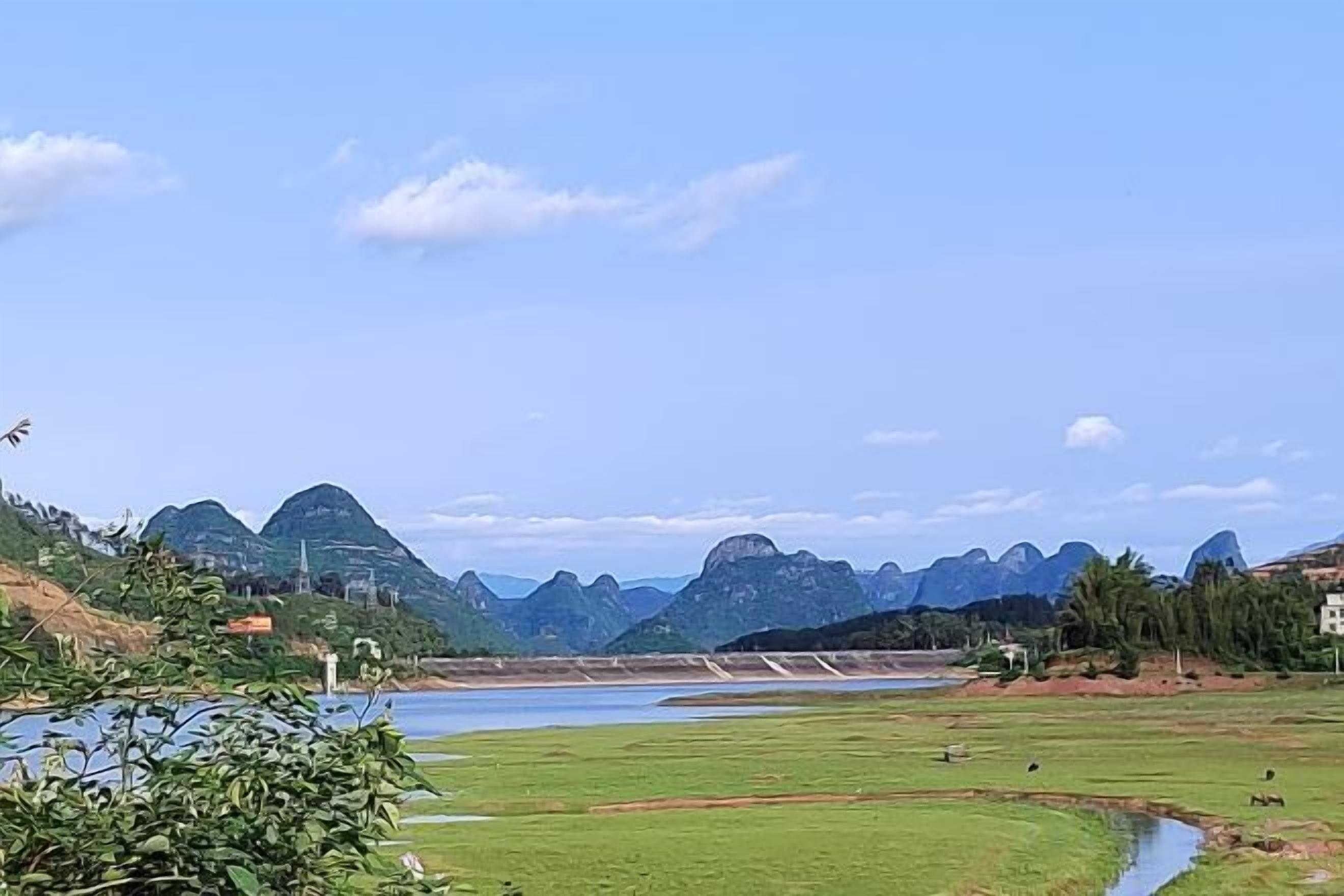 A river with mountains in the background and a bridge across it.