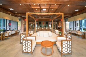 Un espacio interior amplio con una disposición central de asientos, techo de madera y ventanas grandes.