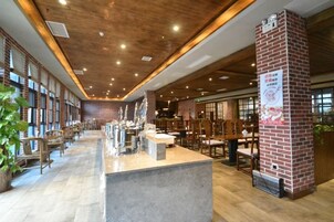 Un restaurante espacioso con una barra larga, techo de madera y detalles de ladrillo.