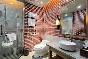 Un baño moderno con cabina de ducha de vidrio, inodoro blanco y un lavabo grande y redondo.