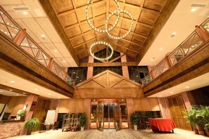Eine großzügige Lobby mit hoher Decke, einer zentralen Treppe und einem Empfangstresen.