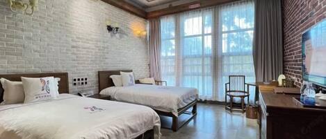 A hotel room with two beds, a desk, and a window with curtains.