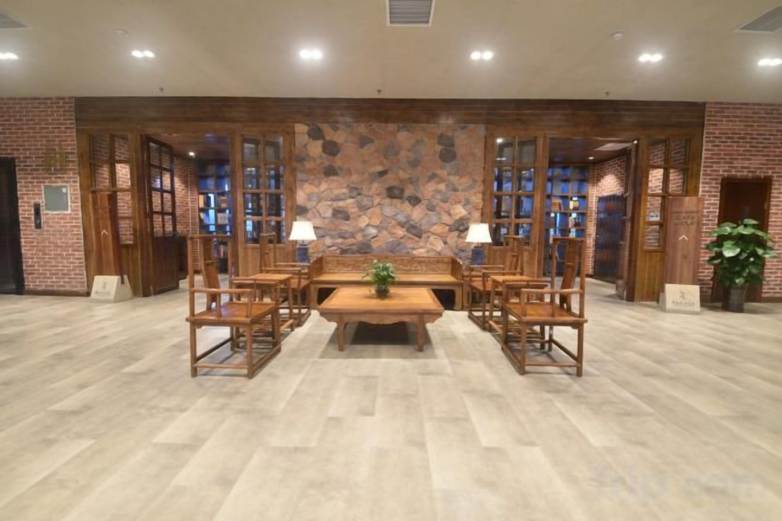 Un salón de conferencias con una larga mesa y sillas, una pared de piedra y una pared de ladrillo con ventanas.