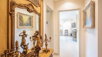 A hallway with ornate gold-framed mirrors and a wooden console table with brass candelabras.