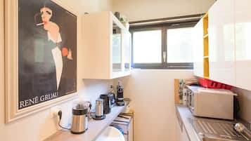 A kitchen with a coffee maker, toaster, and a poster on the wall.