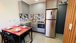 Cocina compacta con refrigerador, estufa, microondas y comedor con mesa lista para cuatro.