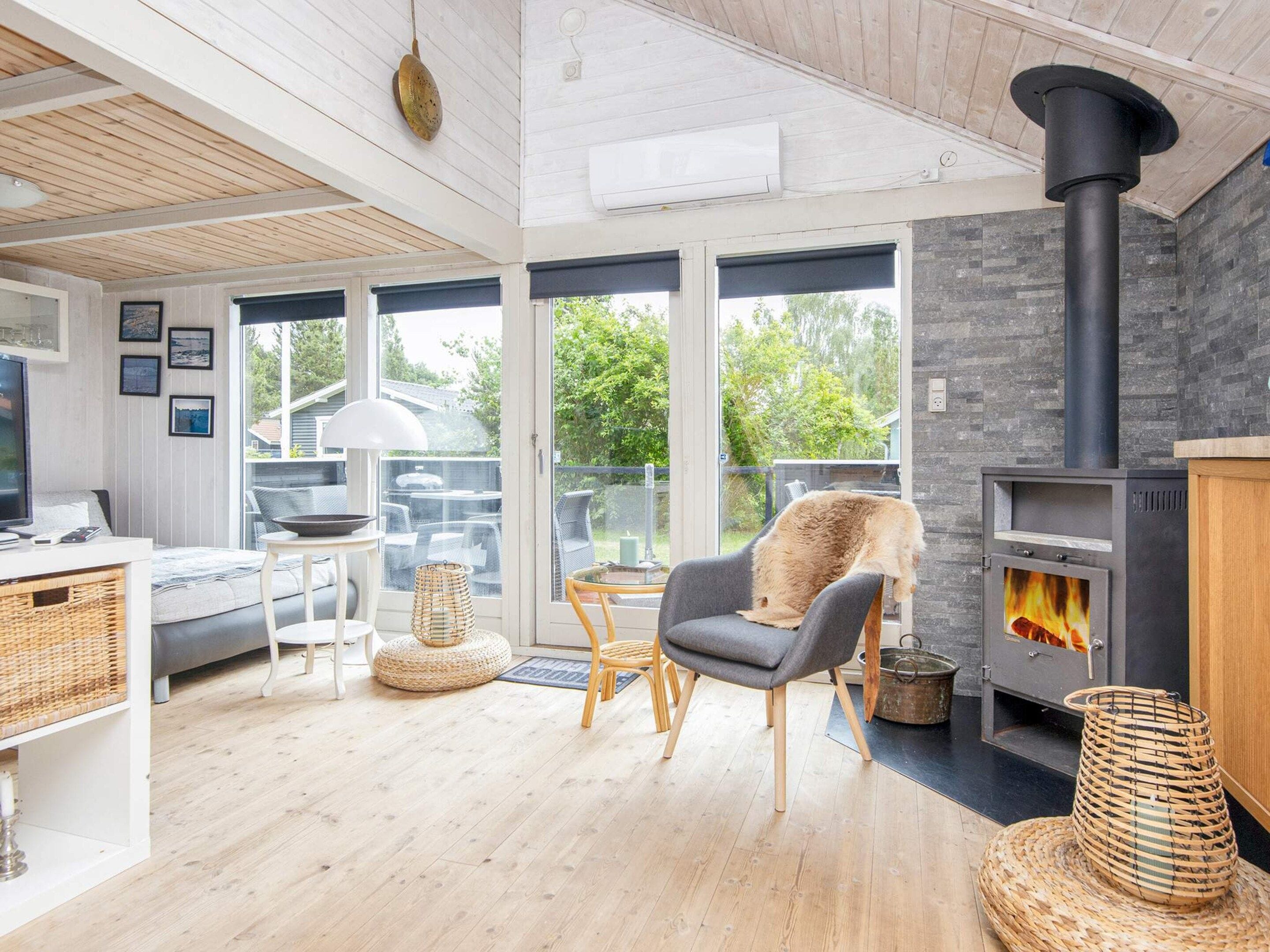A modern living room with a fireplace, a sofa, a dining table, and a large window.