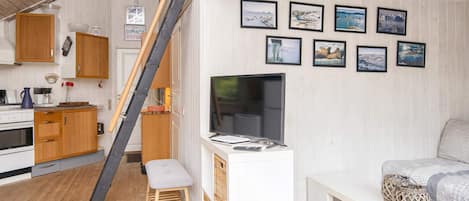 A compact living space with a kitchen, a dining area, and a seating area with a TV.