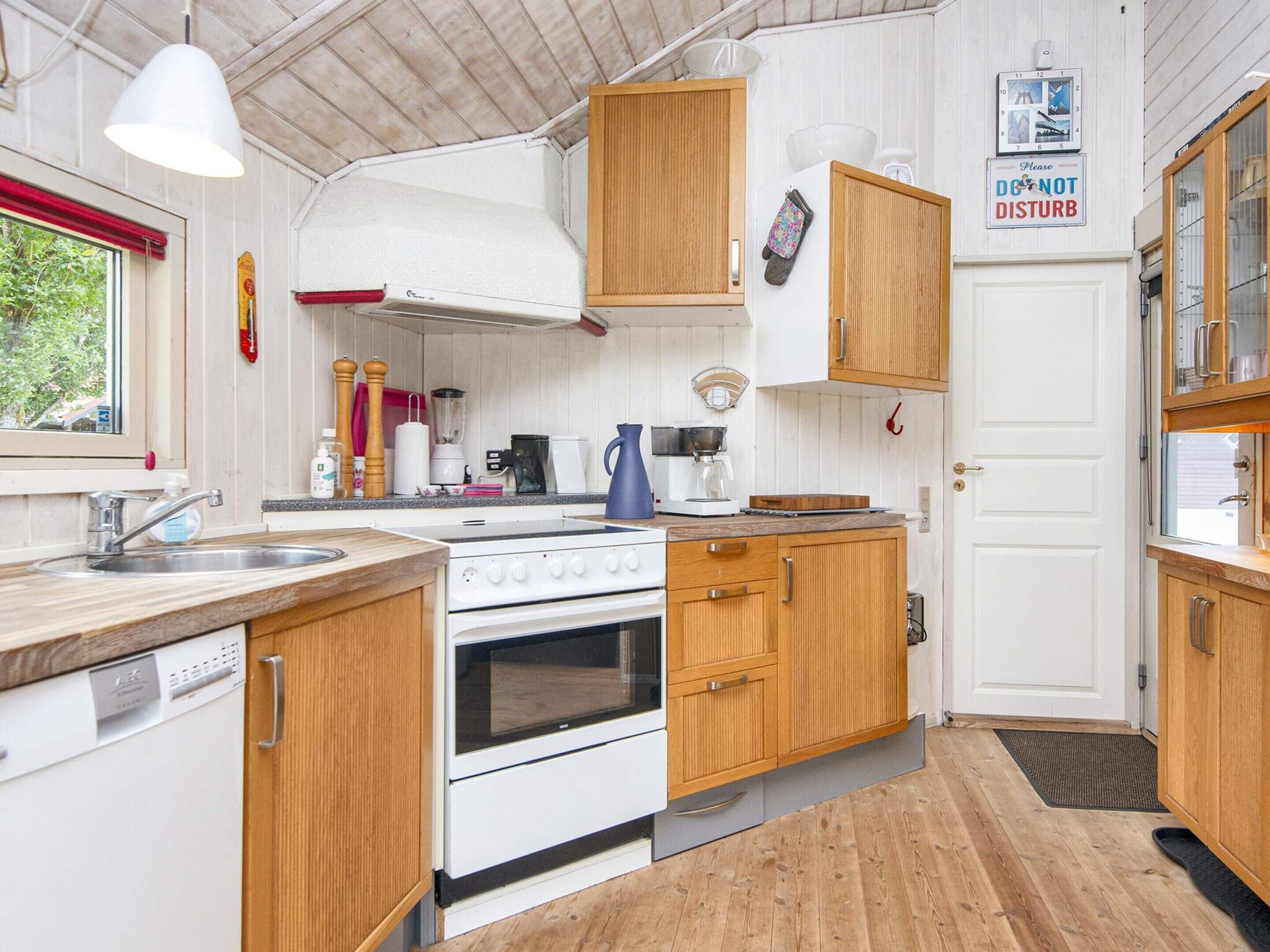 A compact kitchen with wooden cabinets, a white stove, and a sink.