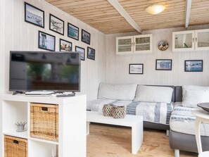 A cozy living room with a television, white furniture, and framed pictures on the wall. - 5 Person Holiday Home in Hovborg (Hovborg)