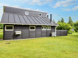 A two-story house with a sloped roof, a chimney, and a fenced yard. - 5 Person Holiday Home in Hovborg (Hovborg)