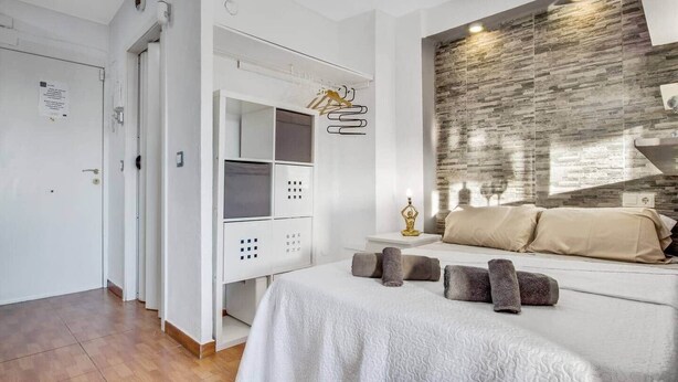 Un dormitorio con cama, mesita de noche, lámpara de pared y armario.