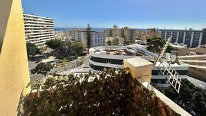 Vista desde un balcón sobre un paisaje urbano con edificios, cielo despejado y una calle abajo.