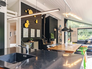 A modern kitchen with a black countertop, a wooden dining table, and a black pendant light. - 5 Star Holiday Home in Bogense (Bogense)