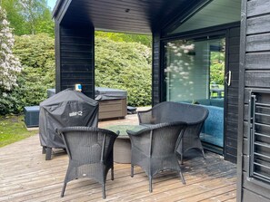 An outdoor deck with wicker furniture, a grill, and a hot tub.