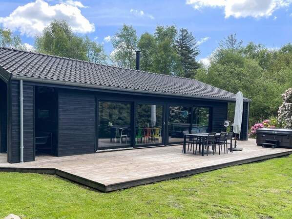 A modern building with a covered patio area, large windows, and a wooden deck.