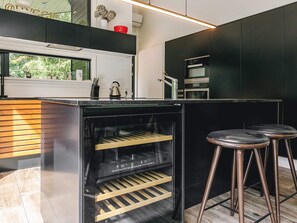 A modern kitchen with a built-in oven, a stainless steel range hood, and a window with a view of greenery. - 5 Star Holiday Home in Bogense (Bogense)