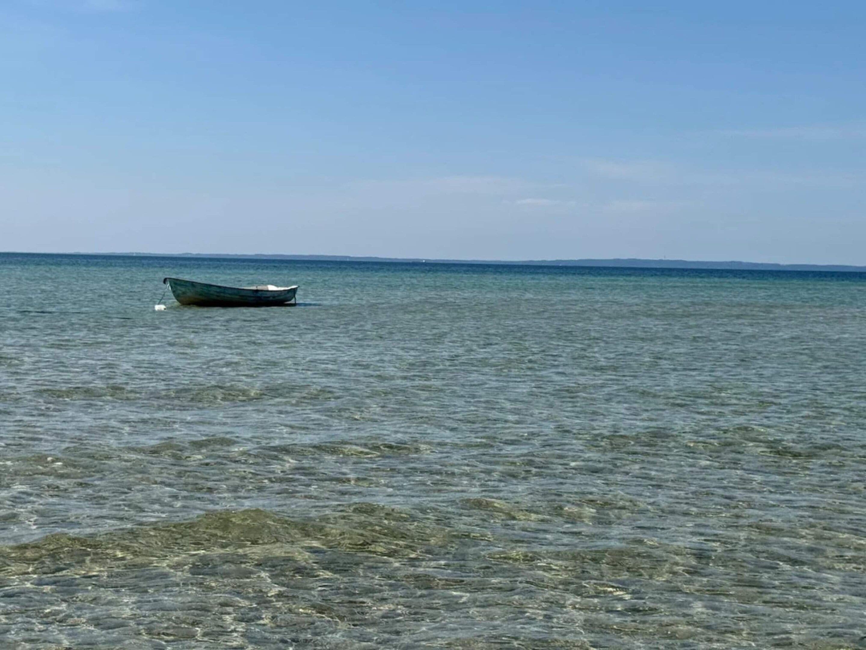 A calm sea with a boat floating on the water.