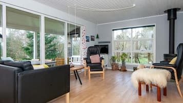 A modern living room with a fireplace, large windows, and a cozy seating area.