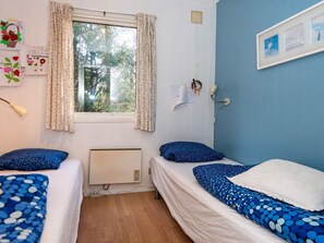 A room with two beds, a window with curtains, a radiator, a wall-mounted lamp, and a framed picture. - 6 Person Holiday Home in Knebel (Knebel)