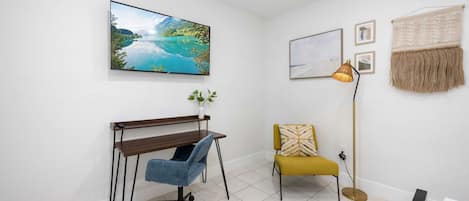 Una habitación con escritorio, silla y televisor montado en la pared.