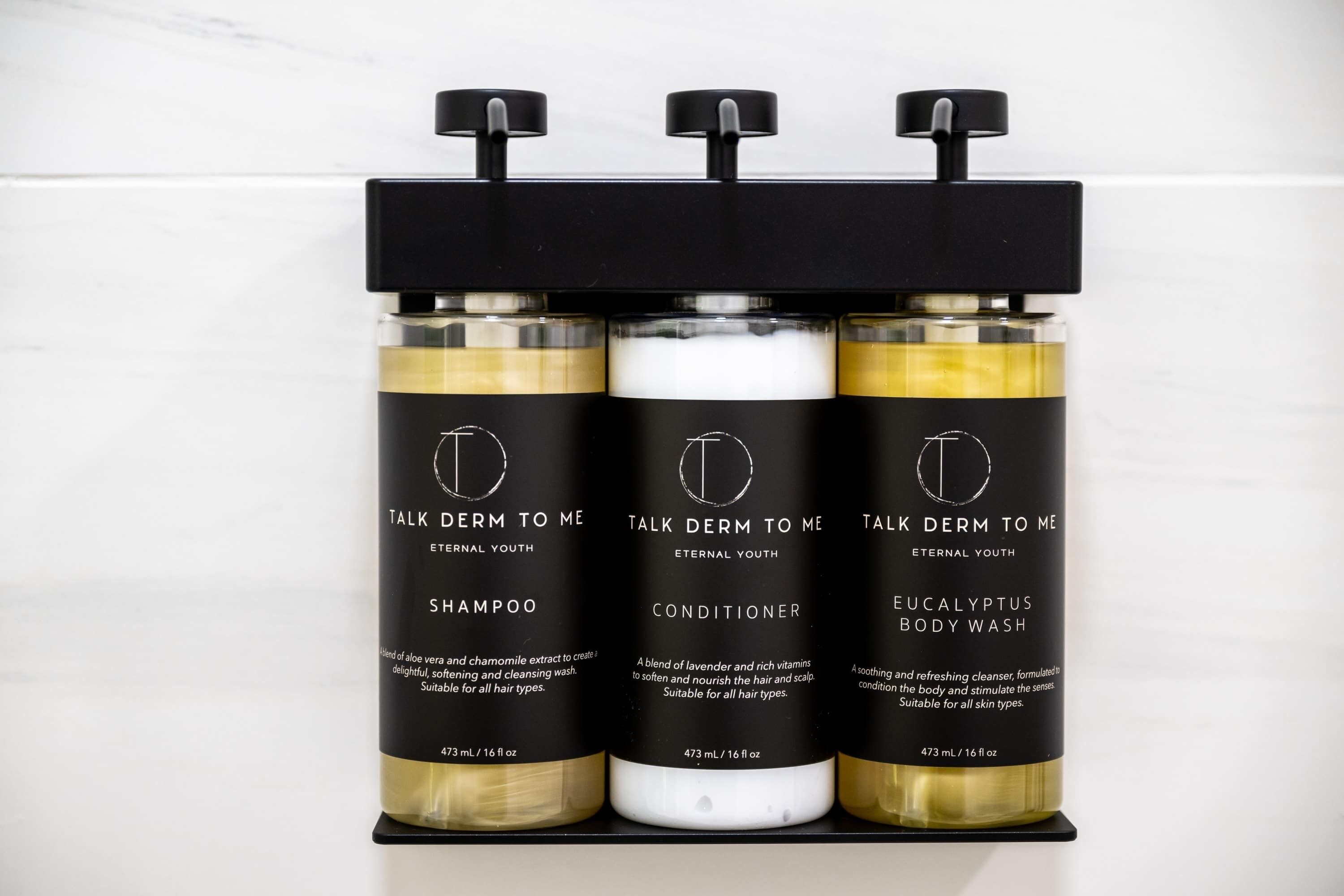 Three bottles of skincare products on a black shelf.