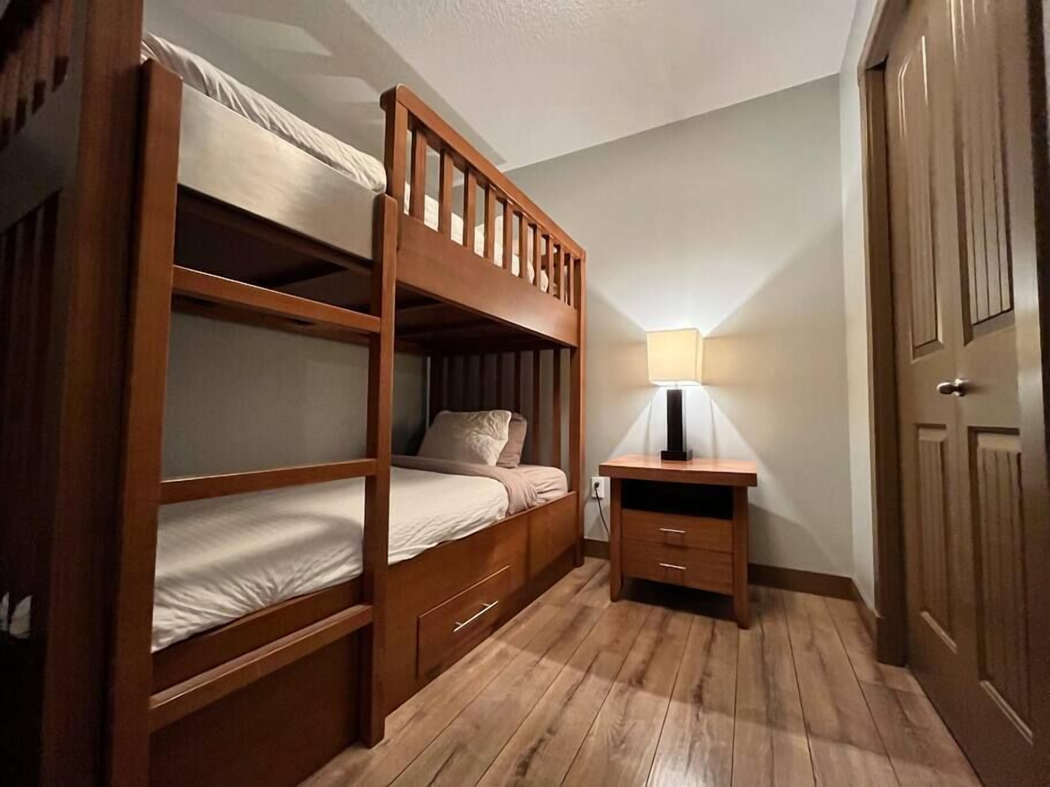 A bunk bed room with a desk and lamp.