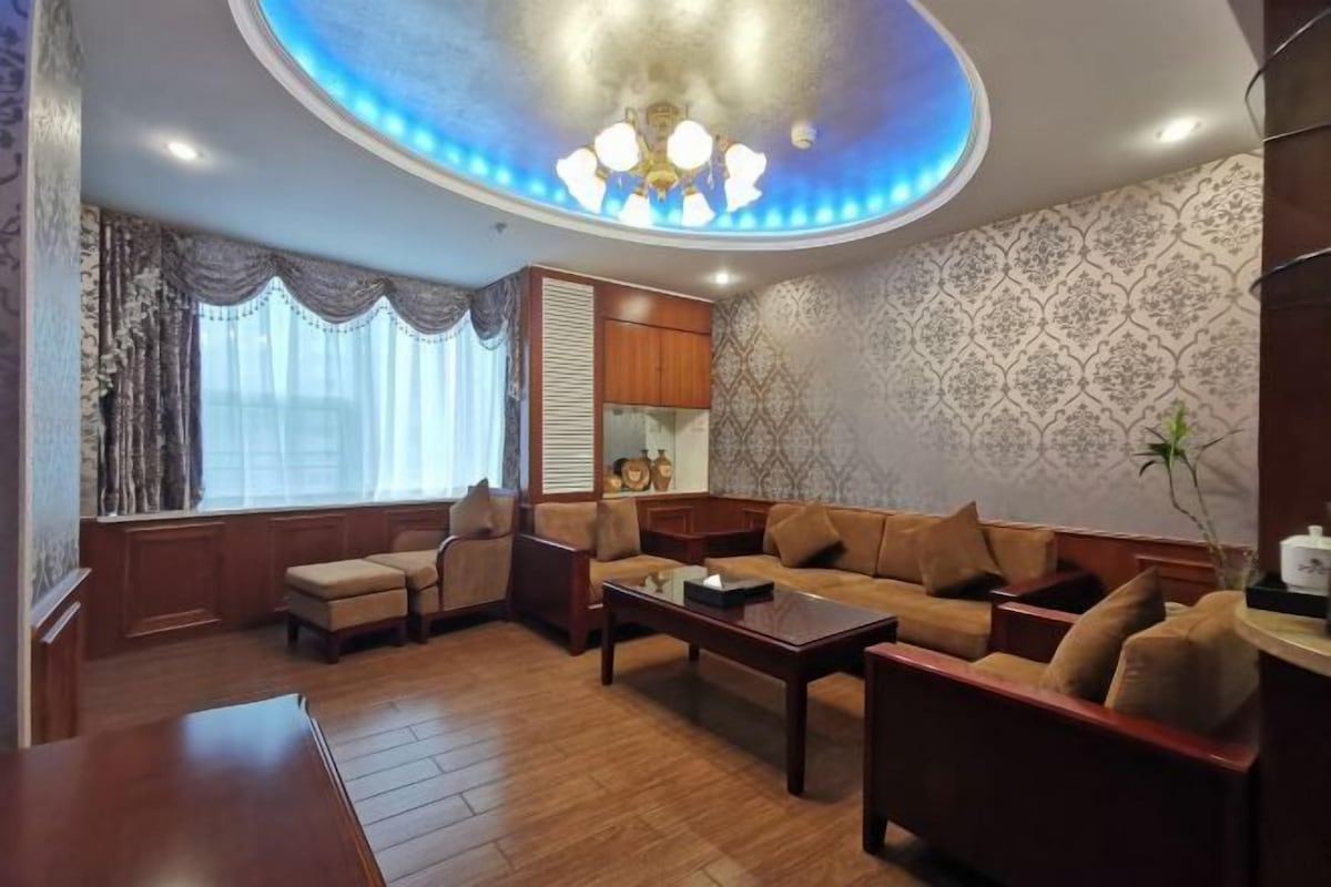 A living room with a sofa, armchairs, a coffee table, and a ceiling light fixture.