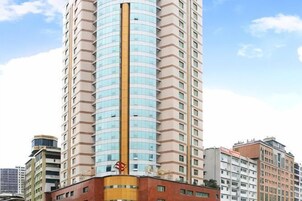 A tall, cylindrical hotel with a central vertical feature, surrounded by other buildings.