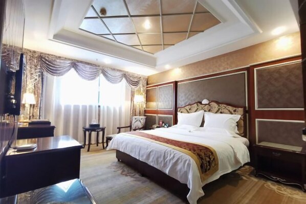 A hotel room with a large bed, a desk, and a chair.