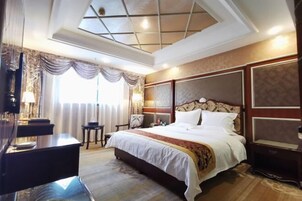 A hotel room with a large bed, a desk, and a chair.