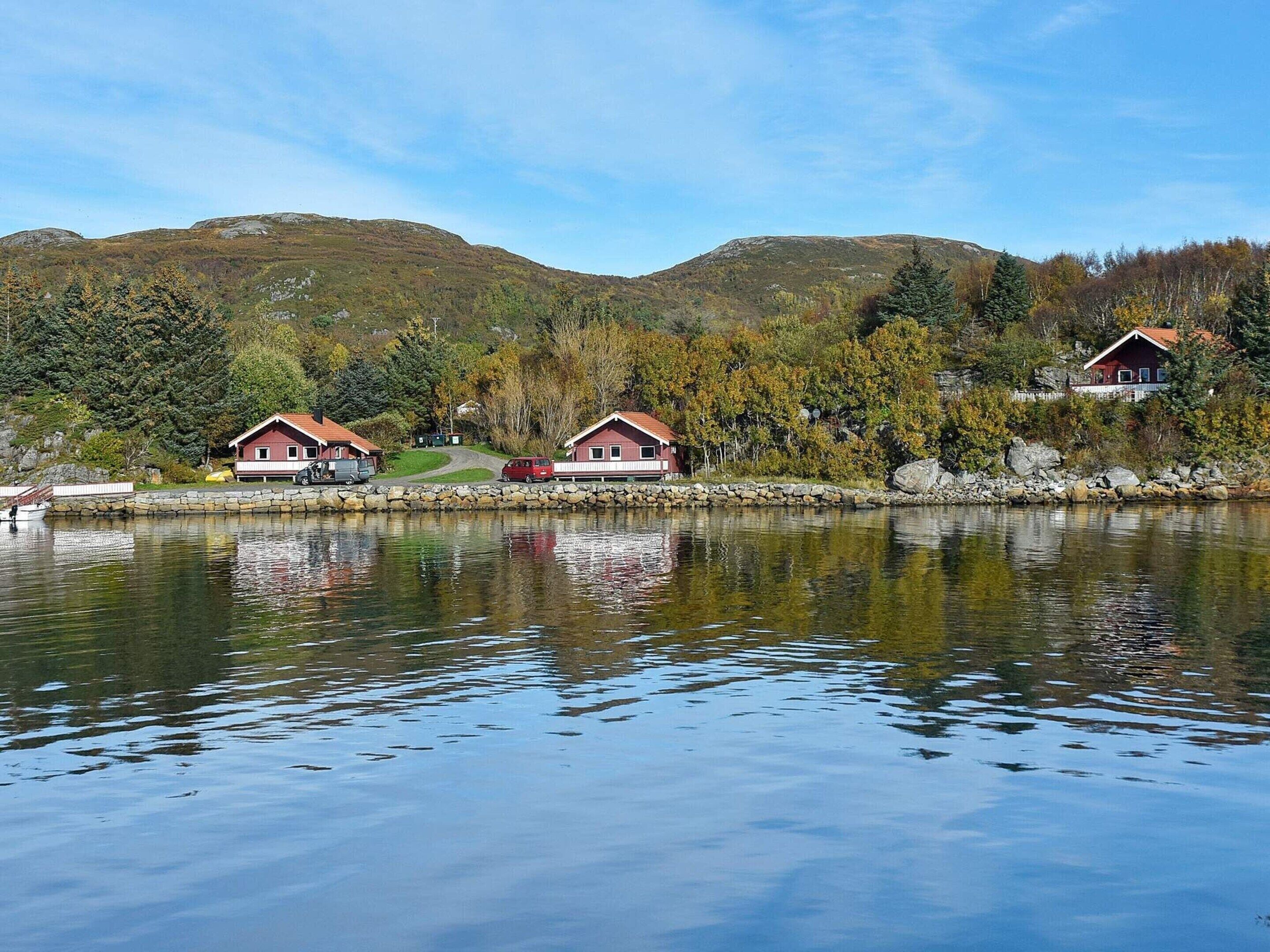 Eine Holzhütte am Seeufer mit Steinwand und Steg.
