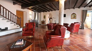 Amplia sala de estar con sofás de cuero rojo, una mesa de centro de madera y una escalera con barandales de madera.