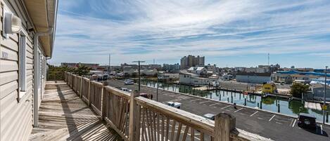 A wooden deck overlooking a marina with boats, a parking lot, and buildings in the background.