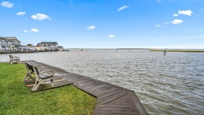 A wooden dock extending into calm water with a grassy area and benches on the left. - Great Midtown Location with Water Views! (Ocean City)