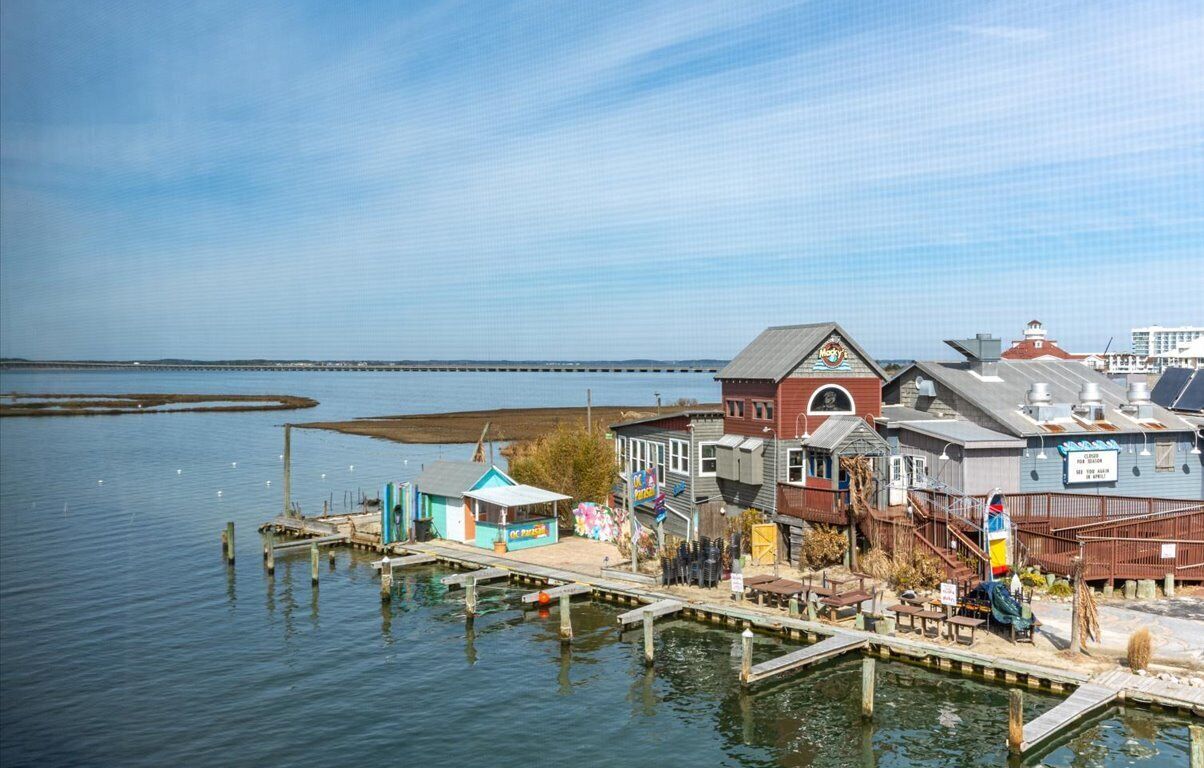 A waterfront property with a dock, a small building with a red roof, and a signboard.