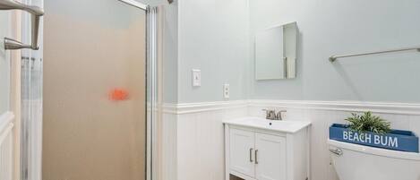 A bathroom with a shower, a toilet, a sink, and a mirror.