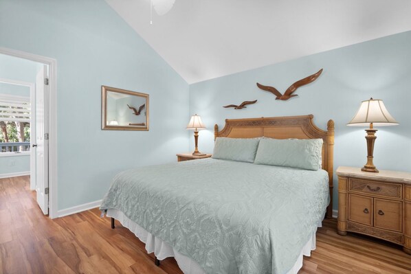 Camera da letto con un letto, due comodini, una testiera in legno, uno specchio fissato alla parete e decorazioni murali.