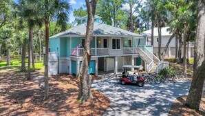 A two-story house with a balcony, surrounded by trees. - "Palm Paradise" Golf cart included. (Fripp Island)