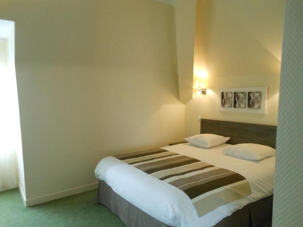 A single bed with a striped bedspread, a headboard, and two wall-mounted light fixtures.