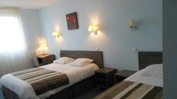 Une chambre d’hôtel avec deux lits, une table de chevet et des lampes fixées au mur.