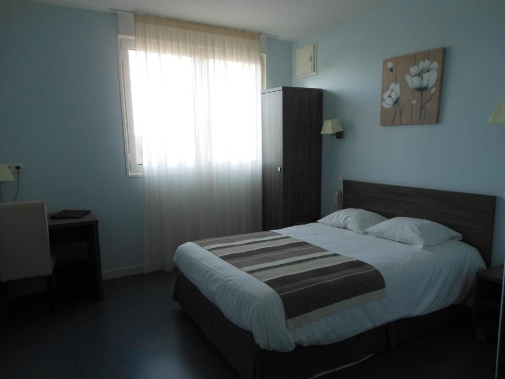 Quarto com cama, escrivaninha, guarda-roupa e janela com cortinas.