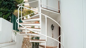 Un escalier en colimaçon avec des rampes blanches et des marches en bois menant à l’étage supérieur.