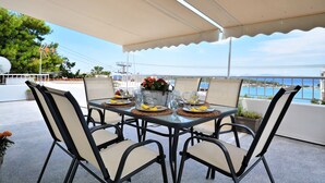 Une table dressée pour quatre personnes, avec vue sur la mer et les montagnes en arrière-plan.