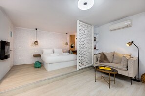 Un dormitorio moderno con cama, sofá, mesita de centro y televisor.