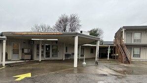 A motel with a covered parking area, a staircase, and a sign indicating an office.