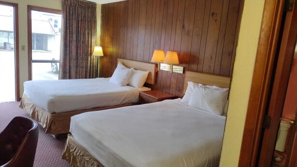 A hotel room with two beds, a desk, and a chair.