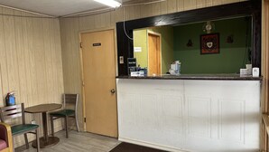 A reception area with a wooden door labeled "PRIVATE," a reception desk with a mirror, and a small table with chairs.